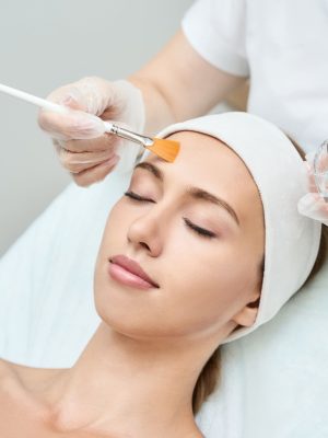 A beautiful woman undergoing a chemical peel treatment, aimed at rejuvenating and revitalizing her skin.